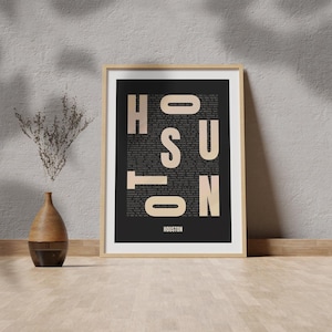 Peut inclure: Une impression encadr&eacute;e avec un fond noir et le mot "HOUSTON" &eacute;crit en grandes lettres beiges. Les lettres sont compos&eacute;es de texte plus petit, cr&eacute;ant un design typographique unique.