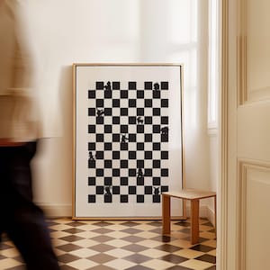 May include: A framed black and white art print featuring a chessboard design with whimsical animal silhouettes in place of chess pieces. The artwork is displayed in a room with a wooden side table and checkered flooring.