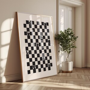 May include: Framed art print featuring a black and white checkerboard design with whimsical animal silhouettes in place of chess pieces. The artwork is displayed in a gold-toned frame, leaning against a wall in a well-lit room.