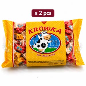 May include: A package of two bags of Krówka milk cream fudge sweets. The yellow packaging features a cartoon cow, the text "KRÓWKA", "MORUS DELUXE", "MILK CREAM FUDGE", and "NET WT. 2.2 lbs / 1 kg". The sweets are individually wrapped in red and yellow.