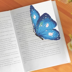 Op de afbeelding: Een open boek met een blauwe vlinder-bladwijzer. De vlinder heeft witte stippen en een glinsterende textuur. De tekst op de pagina gaat over een bedrijf en zijn werknemers.