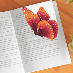 May include: A close-up of an open book with a colourful butterfly design printed on the page. The butterfly is made up of small, colourful squares, creating a pixelated effect. The text on the page is about a company's commitment to reliability and customer service.