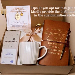 May include: Gift box with a gold necklace, a chocolate bar, a white mug, a journal, and a pen. The journal reads "May you be proud of the work you do." The box includes a bow and the text "You Are Loved."