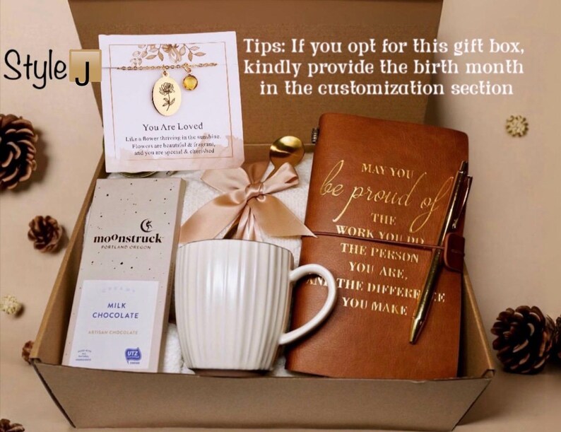 May include: Gift box with a gold necklace, a chocolate bar, a white mug, a journal, and a pen. The journal reads "May you be proud of the work you do." The box includes a bow and the text "You Are Loved."