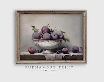 May include: A framed still life print featuring a silver bowl overflowing with ripe plums and grapes. The fruit is a deep purple color, contrasted against the white bowl and a neutral background. The print is labeled "PUDNAMBUT PRINT".
