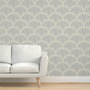 May include: A white sofa sits in front of a wall covered in a light blue and cream wallpaper with a geometric fan pattern.