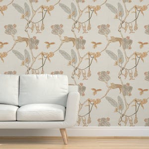 May include: Wallpaper with a repeating pattern of jungle scenes. The design includes branches, leaves, flowers, and small animals in shades of tan, grey, and peach against a cream background. A white sofa is in the foreground.