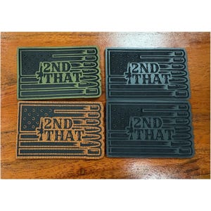 May include: Four rectangular patches with a flag design and the text "2ND THAT". The patches are in shades of green, gray, and brown. The design includes stars, stripes, and a rifle.
