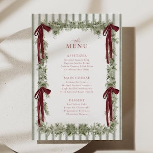 May include: A menu card with a green and white striped background, adorned with a garland of greenery and burgundy bows. The menu lists appetizers, main courses, and desserts. The word "MENU" is at the top.