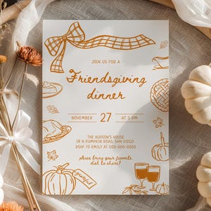 May include: An invitation for a Friendsgiving dinner, featuring a bow and autumnal illustrations. The invitation is surrounded by white pumpkins, dried flowers, and a bamboo ring. The text reads "Friendsgiving dinner" and the date.
