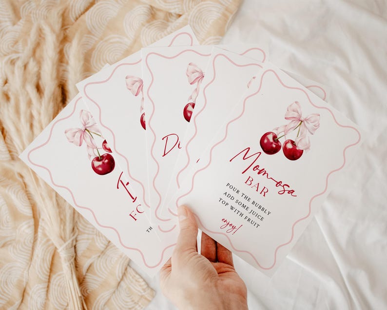 May include: Four white cards with pink scalloped edges and pink ribbons with cherries. The top card says "Momosa Bar" with instructions to "Pour the bubbly, add some juice, top with fruit, enjoy!"