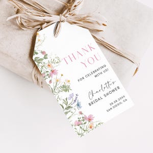 May include: A white thank you tag with a floral border. The text reads "Thank You for celebrating with us! Charlotte's Bridal Shower 28.08.20XX San Diego, CA".