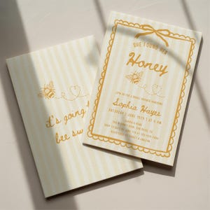 May include: Two light yellow and white striped bridal shower invitations. One invitation reads "She found her Honey" with a bee graphic. The other reads "It's going bee sw". The invitations include event details.