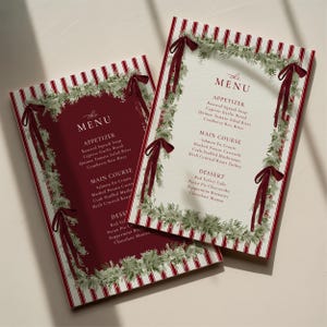 May include: Two menu cards with a festive design. Each card features a red background with white stripes and a decorative border of greenery and red ribbons. The menu includes appetizers, main courses, and desserts.