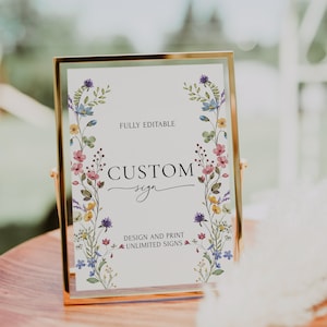 May include: A gold-framed sign with a white background and a floral border. The sign says "FULLY EDITABLE CUSTOM sign DESIGN AND PRINT UNLIMITED SIGNS".