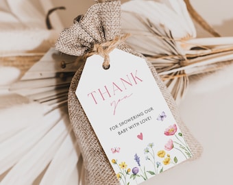 May include: A white thank you tag with pink lettering that says "THANK you" and "FOR SHOWERING OUR BABY WITH LOVE!" with a pink heart. The tag is decorated with watercolor flowers and butterflies and is tied to a small burlap bag.