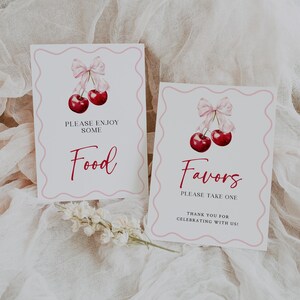 May include: Two white signs with pink borders and cherry illustrations. The top sign says "Please enjoy some Food" and the bottom sign says "Favors Please take one Thank you for celebrating with us!"
