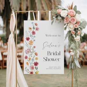 May include: A white sign with a floral border and the text "Welcome to Selena's Bridal Shower August 28th, 2026 San Diego, California".