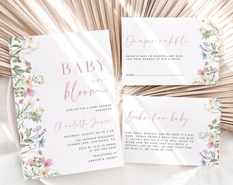 May include: Baby shower invitation and cards with floral accents. The invitation reads "Baby in Bloom" and includes event details. Cards for a diaper raffle and books for baby are also included. The design features pink script and delicate flower illustrations.