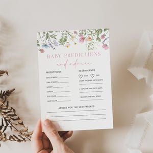 K&ouml;nnte beinhalten: Eine Babyparty-Spielkarte im floralen Design mit dem Titel "Baby-Vorhersagen und Ratschl&auml;ge". Die Karte enth&auml;lt Abschnitte, in denen die G&auml;ste das Geburtsdatum des Babys, die Geburtszeit, das Gewicht, die L&auml;nge, die Augenfarbe, die Haarfarbe und die &Auml;hnlichkeit mit den Eltern vorhersagen k&ouml;nnen. Au&szlig;erdem gibt es einen Abschnitt f&uuml;r Ratschl&auml;ge f&uuml;r die frischgebackenen Eltern.