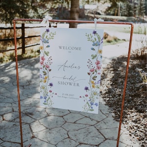 May include: A white sign with a floral border and the text "Welcome to Amelia's Bridal Shower 21.08.2027 San Diego, California".