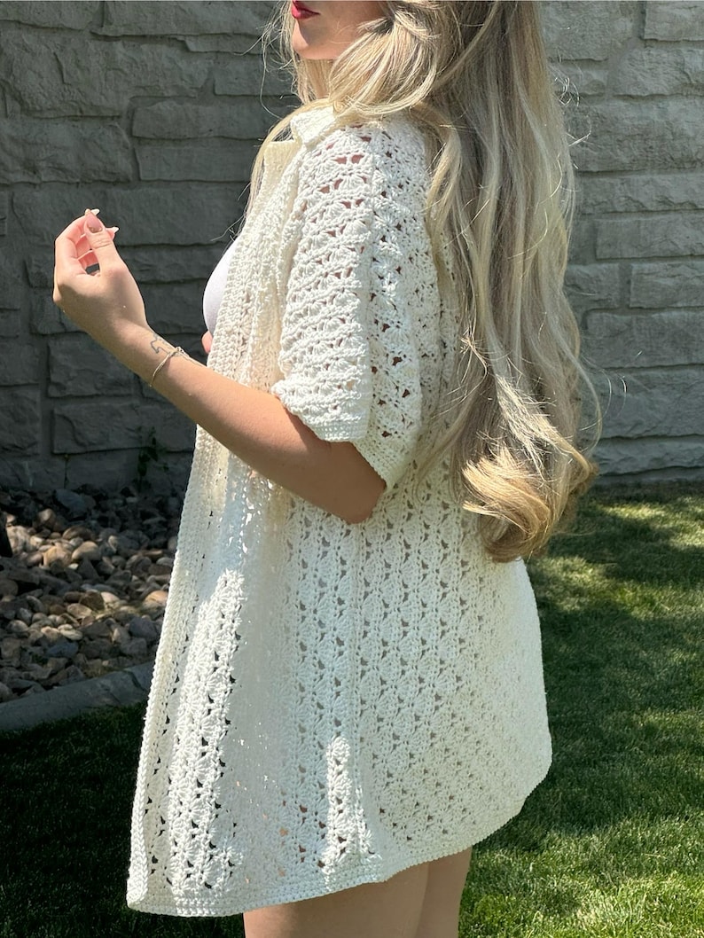 May include: A white crochet cardigan with a loose fit and short sleeves. The cardigan has a delicate openwork pattern.