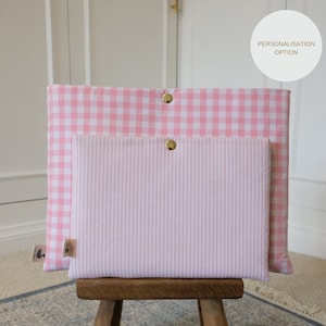 Op de afbeelding: Roze en witte gingham en gestreepte laptophoes van stof met gouden knopen. Personalisatie-optie.
