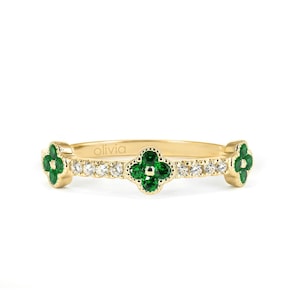 Pode incluir: Um anel de banda de ouro com três engastes em forma de trevo verde com pequenos diamantes em torno de cada trevo. O anel é gravado com a palavra "olivia".