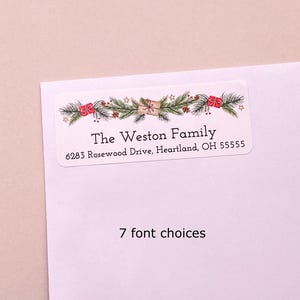 May include: A rectangular address label featuring a festive holiday illustration of pine branches, red gift boxes, and small stars. The text reads The Weston Family, 6283 Rosewood Drive, Heartland, OH 55555. Below the label, the text 7 font choices appears.