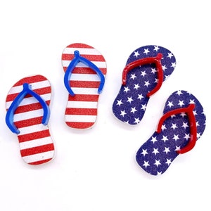 May include: Three pairs of flip-flops with an American flag design. One pair is red and white stripes, and the other two pairs are blue with white stars.