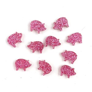 Könnte beinhalten: Zehn rosa glitzernde Schweinefiguren. Die Schweine sind alle in die gleiche Richtung ausgerichtet und haben eine glänzende, glitzernde Oberfläche.