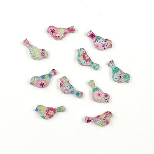 Könnte beinhalten: Zehn kleine, holzartige Knöpfe in Vogelform mit einem Blumenmuster in Rosa-, Grün- und Blautönen.