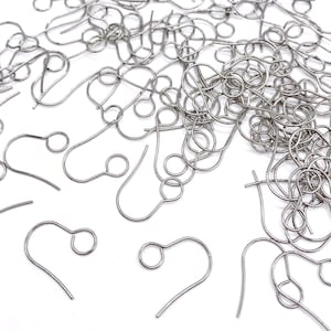 May include: A pile of silver earring hooks, a type of jewelry finding, on a white background.