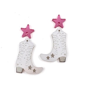 May include: A pair of white cowboy boot earrings with pink star accents. The boots have a cutout design and are made of wood.