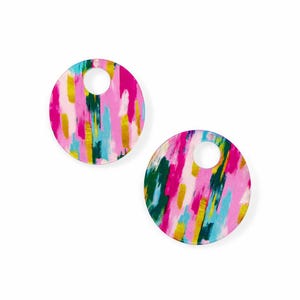May include: Two circular earrings with a hole at the top, featuring an abstract design. The earrings display a pattern of pink, gold, blue, and green brushstrokes against a white backdrop. A colourful accessory.
