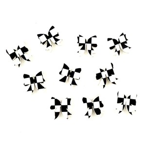 May include: Ten black and white checkered bow hair clips. The bows are made of a white material with black checkered squares.