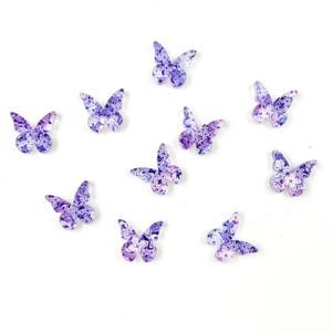 May include: Purple and white butterfly shaped embellishments with a floral pattern.