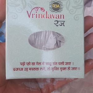 May include: A light green box with maroon Hindi text and the word "Vrindavan". The box has a clear plastic window showing a white substance. Further Hindi text is visible on the box.