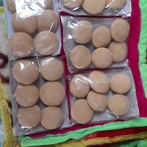 May include: Four packs of round, brown, edible treats, each pack containing six treats. The treats are wrapped in clear plastic and arranged in a grid pattern.