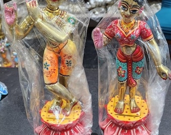 Könnte beinhalten: Zwei farbenfrohe, handbemalte Figuren hinduistischer Gottheiten, die auf lotusförmigen Sockeln stehen. Die Figuren sind in aufwendige Kleidung gekleidet und haben komplizierte Details.