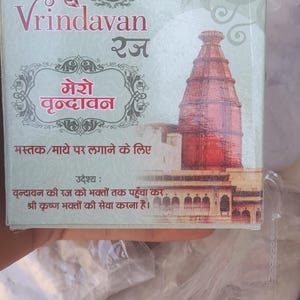 Może przedstawiać: Pudełko z napisem "Vrindavan" w języku angielskim i hindi, z ilustracją czerwonej świątyni. Pudełko zawiera również tekst w języku hindi i angielskim oraz logo RBA.