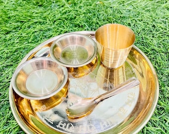 May include: A gold-colored metal plate with a small spoon, two bowls, and a cup. The plate has an inscription in a foreign language.
