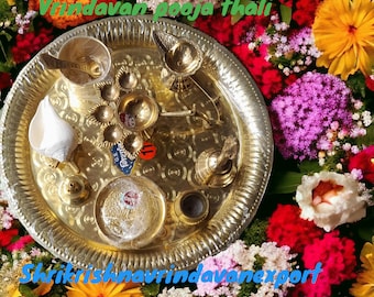 May include: A gold metal puja thali, or ceremonial plate, filled with various items used in Hindu worship. The thali is surrounded by a variety of colorful flowers, including pink, purple, red, and yellow.