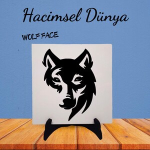 May include: A black and white wolf face silhouette on a white ceramic tile with a black stand. The tile has the text "Hacimsel Dünya" and "WOLF FACE" printed on it.