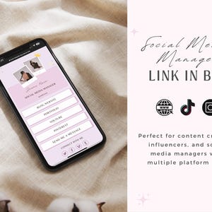 May include: A smartphone displays a social media manager profile with a pink and white design. The screen shows links for a blog, portfolio, YouTube, Pinterest, and contact information. The text "Social Media Manager, LINK IN BIO" is visible.