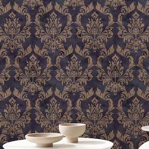 May include: A room interior featuring a dark purple wallpaper with a repeating tan damask pattern. A round white coffee table with gold legs sits in the foreground next to a cream-coloured curved armchair and a small side table with a sculpture.