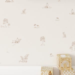 May include: Off-white wallpaper featuring a repeating pattern of light brown illustrations of foxes, trees, and mushrooms. Two wooden blocks with white engraved designs of a rainbow, flowers, and the number 20 sit on a white shelf.