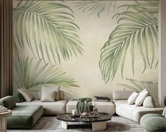 Puede incluir: Salón con un gran mural de hojas de palmera estilo acuarela en tonos verdes sobre un fondo crema. La habitación incluye una alfombra gris, una mesa de centro y un sofá seccional en tonos neutros con cojines verdes y una manta verde.