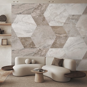 Può includere: Un moderno soggiorno con un divano curvo color crema, un tavolino in legno e un tavolino rotondo. La parete dietro il divano è decorata con grandi piastrelle esagonali nei toni del grigio e del marrone.