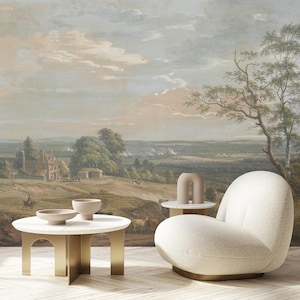 Könnte beinhalten: Ein Wohnzimmerszene mit einem Landschaftsmural, einem weißen, abgerundeten Sessel und zwei kleinen runden Tischen. Die Tische haben goldene Beine und weiße Oberflächen, mit beigefarbenen Schalen und einer dekorativen Vase. Das Wandbild zeigt eine ländliche Szene.